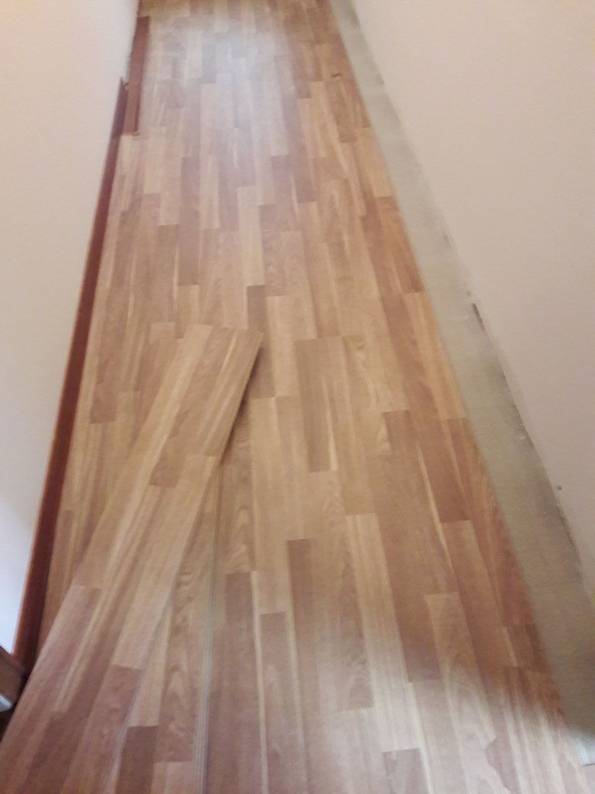 In un corridoio viene installato un pavimento in legno.