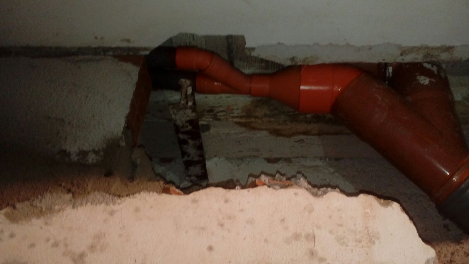 Un tubo rosso esce da un buco nel muro.