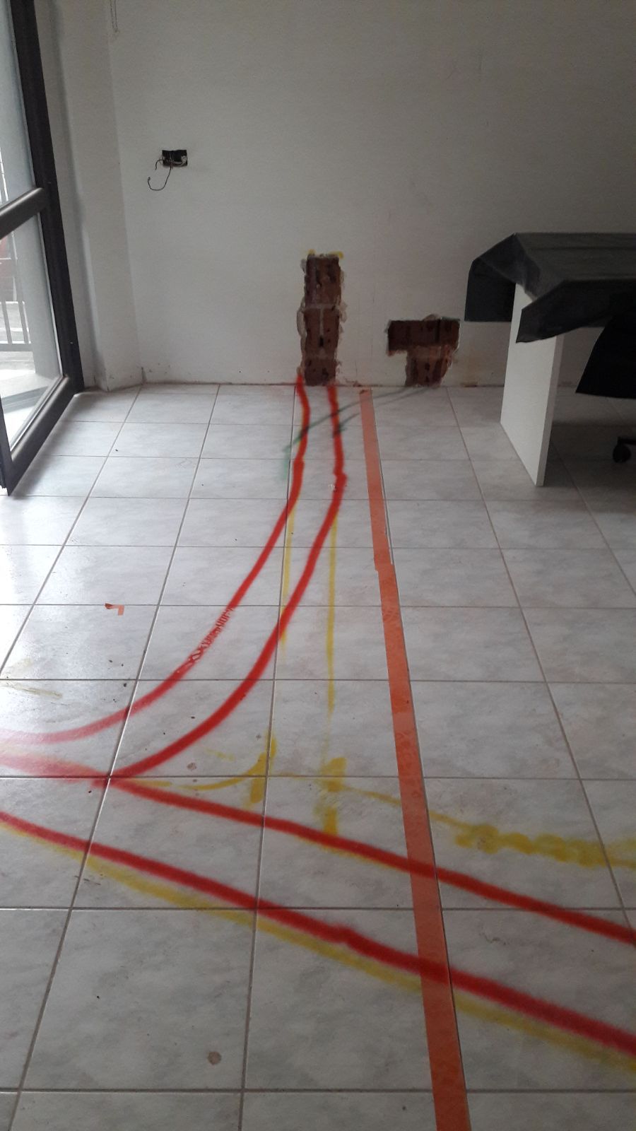 Una stanza con pavimenti piastrellati e nastro adesivo rosso e giallo sul pavimento.