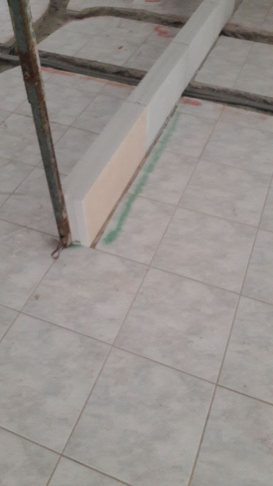 Un pavimento di piastrelle bianche con un palo di metallo al centro.