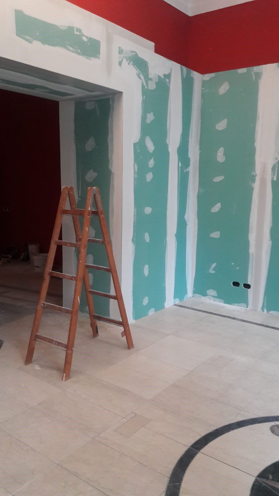 Una scala di legno è appoggiata in una stanza che è in fase di ristrutturazione.