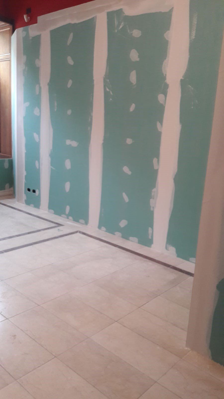 Una stanza con pavimento piastrellato e parete in cartongesso verde.