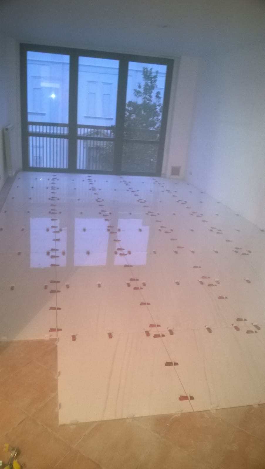 Una grande stanza vuota con pavimento piastrellato e una grande finestra.