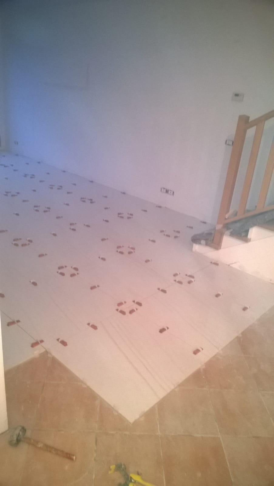 Una stanza con una scala e un martello sul pavimento.