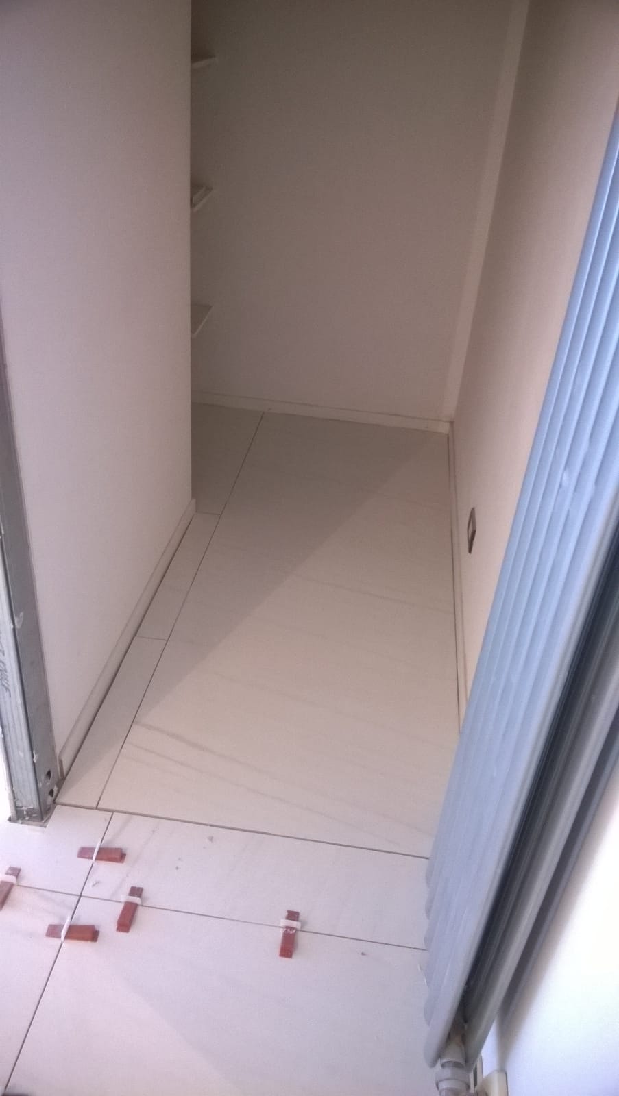 Un corridoio stretto con pavimento piastrellato bianco.