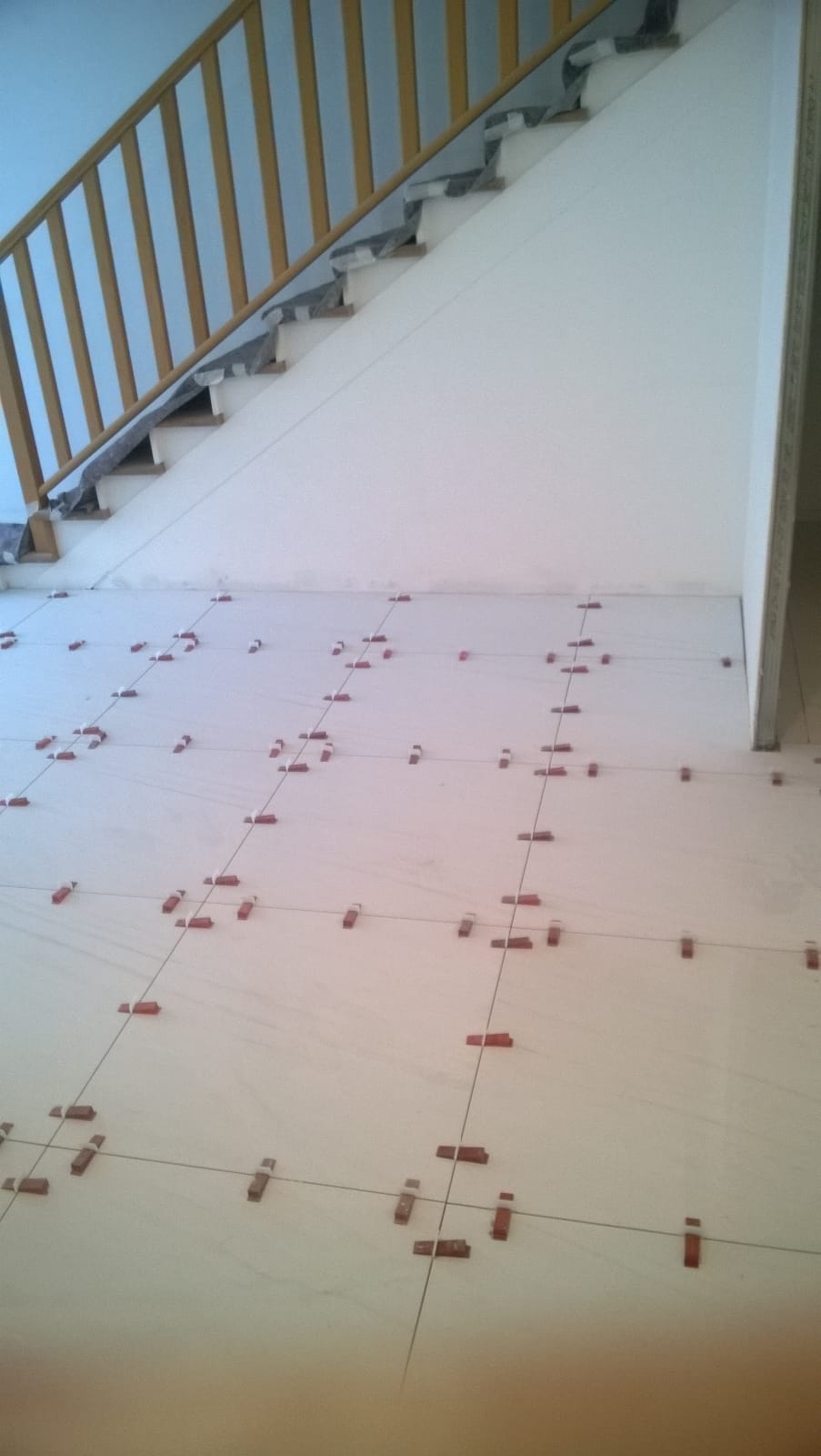 Una scala con ringhiera in legno e pavimento piastrellato.