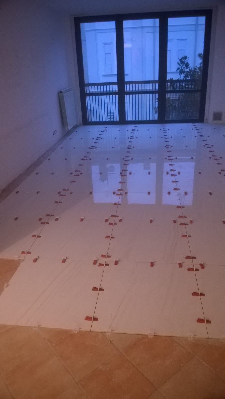 Una stanza con una grande finestra e un pavimento piastrellato bianco