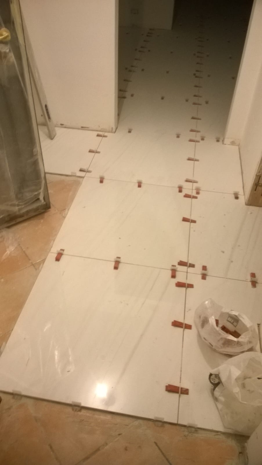 In una stanza viene installato un pavimento in piastrelle bianche.