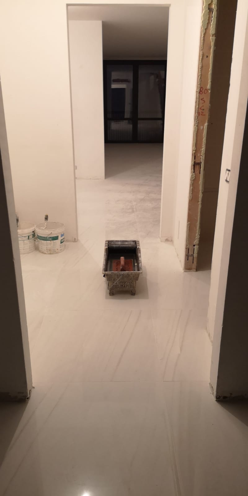 Un pavimento piastrellato bianco in un corridoio tra due porte.