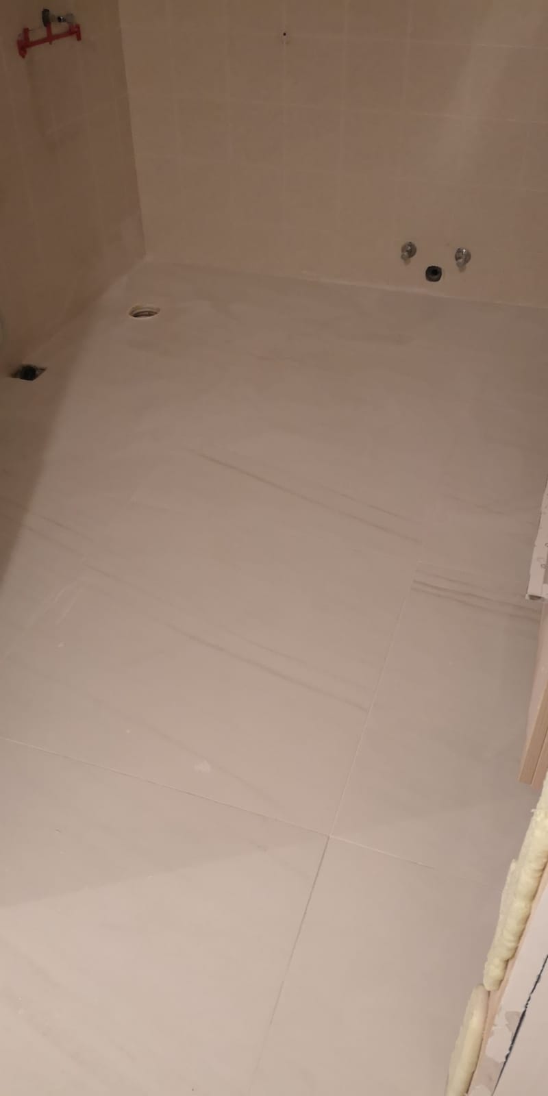 Un pavimento piastrellato bianco in un bagno accanto a una vasca da bagno.