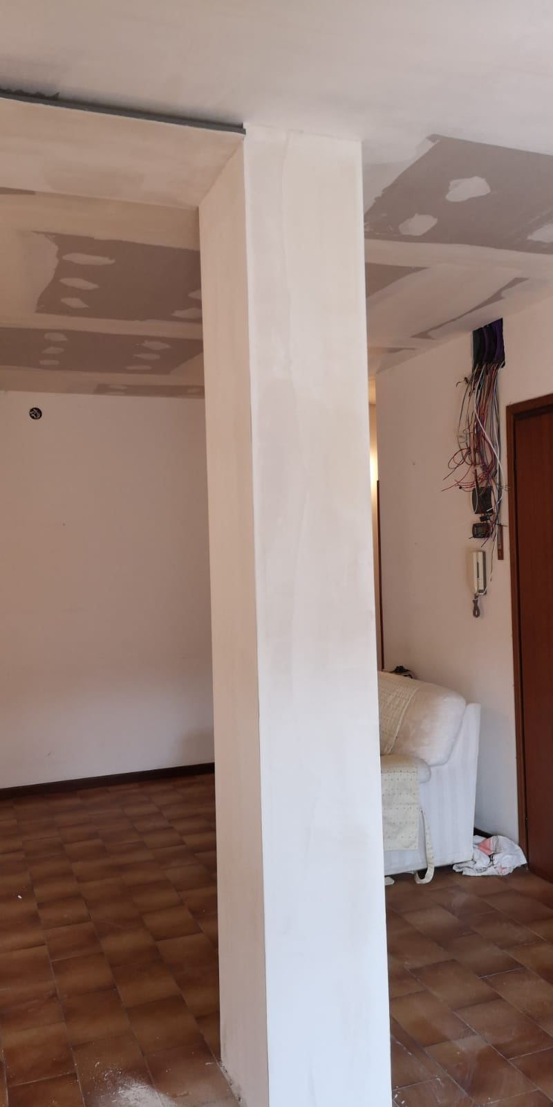 Un soggiorno con un divano e un pilastro al centro.