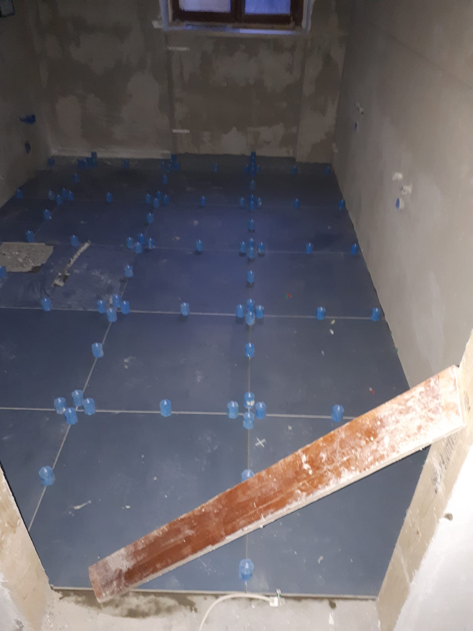 Una stanza con piastrelle blu sul pavimento e una tavola di legno sul pavimento.