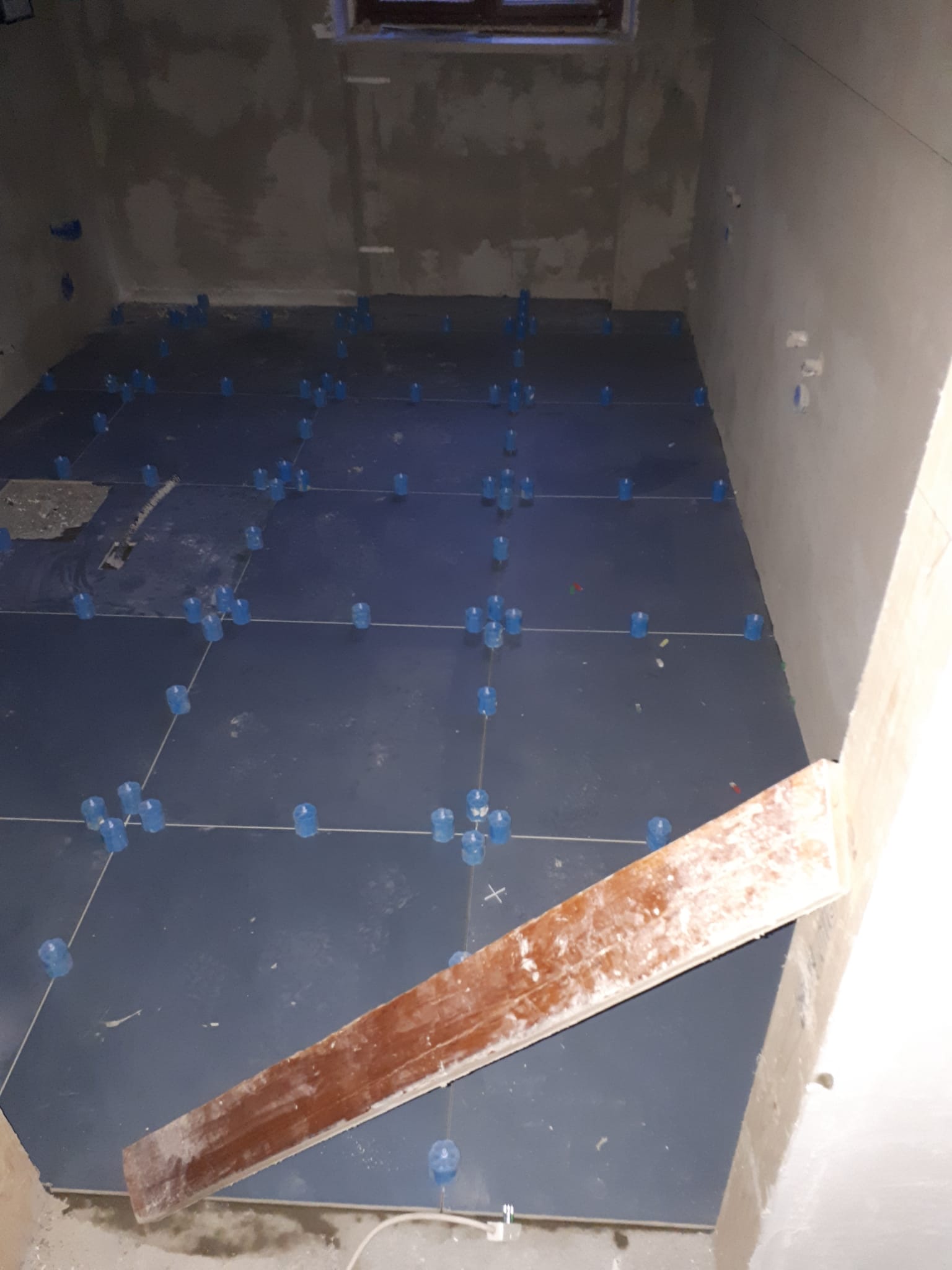 Una stanza con pavimento piastrellato e una tavola di legno sul pavimento.