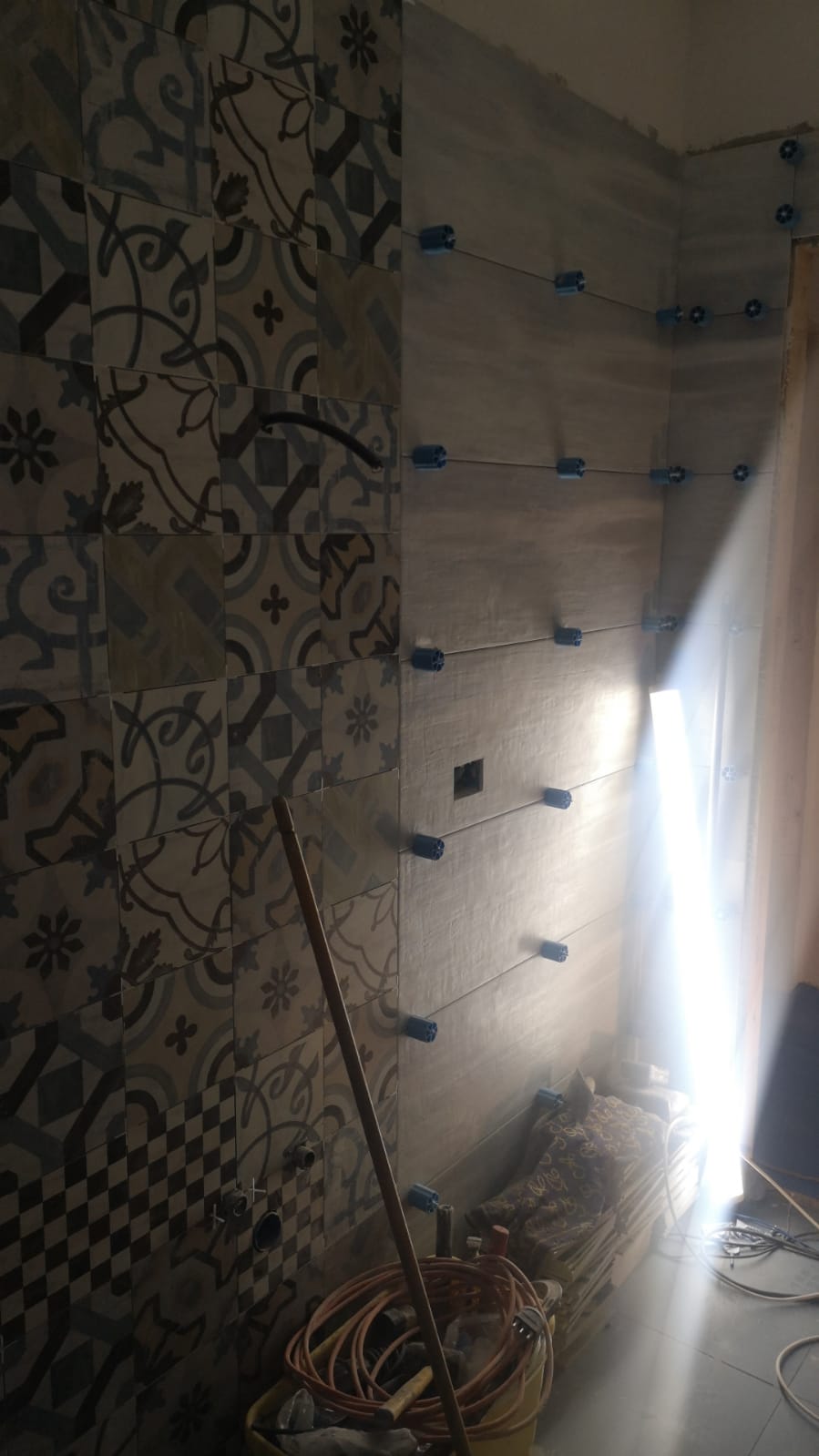 Uno straccio è appoggiato davanti a una parete piastrellata in un bagno.