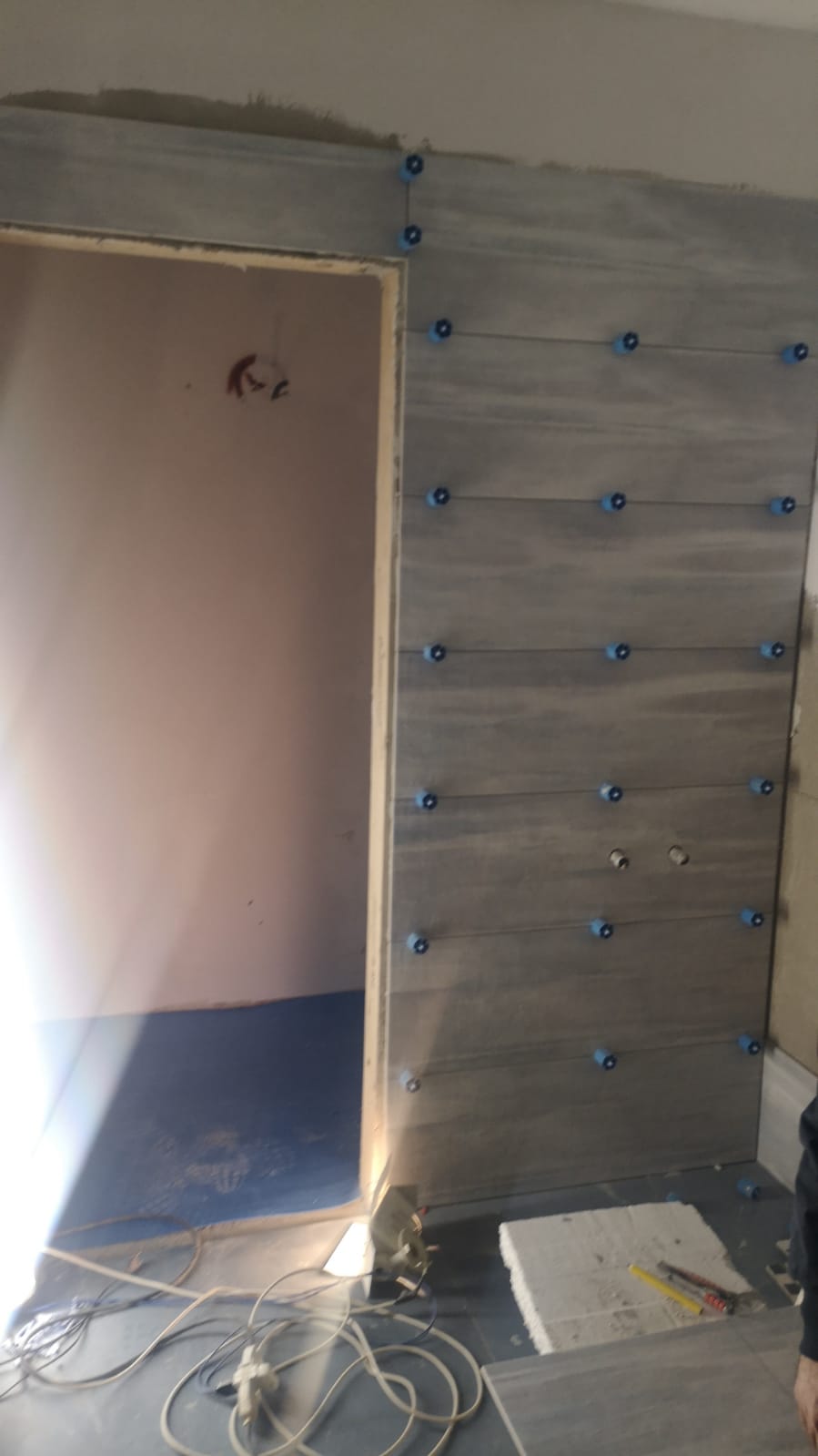 Una persona sta installando delle piastrelle su una parete in una stanza.