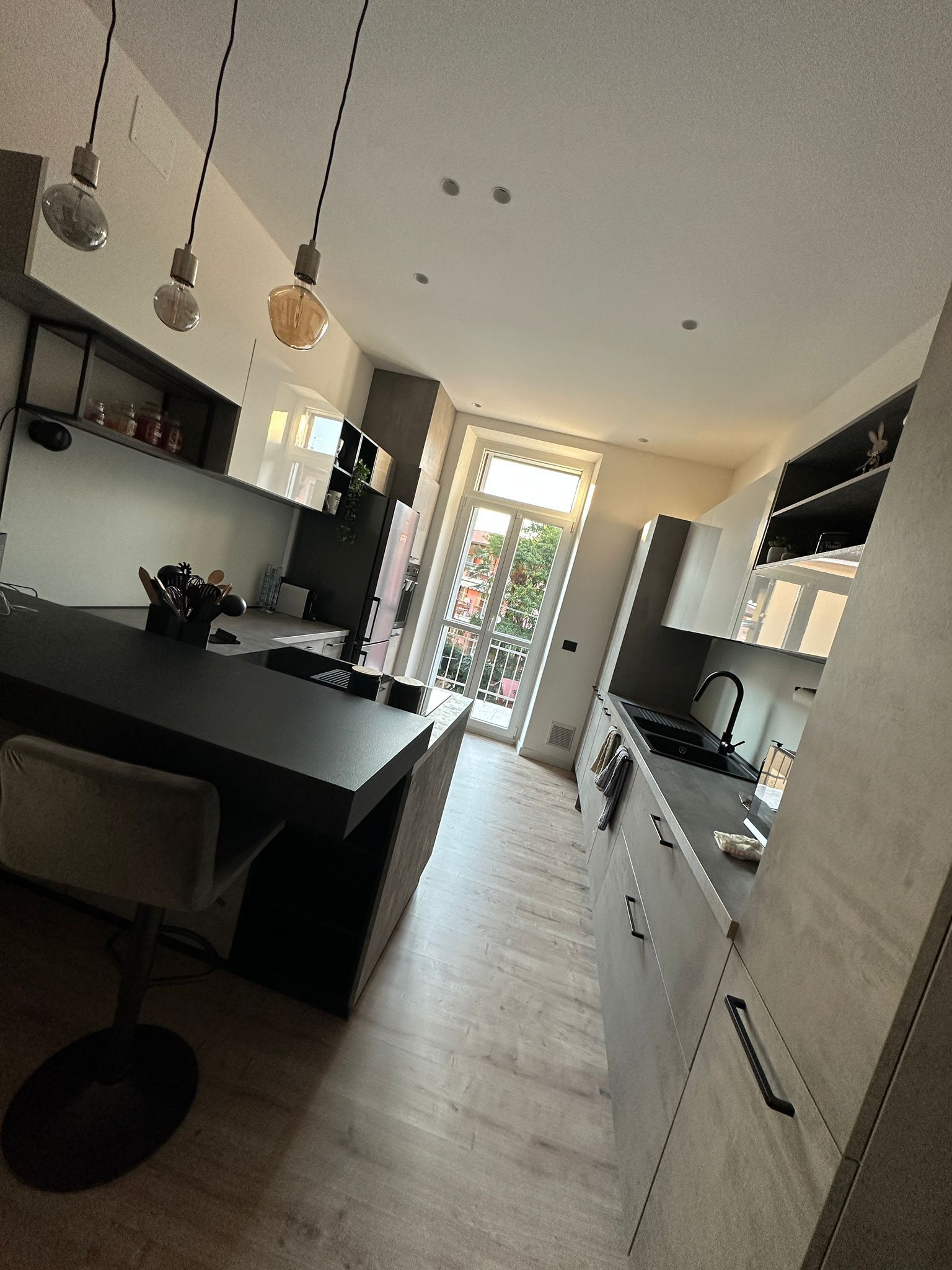 Una cucina con mobili bianchi e un piano di lavoro nero