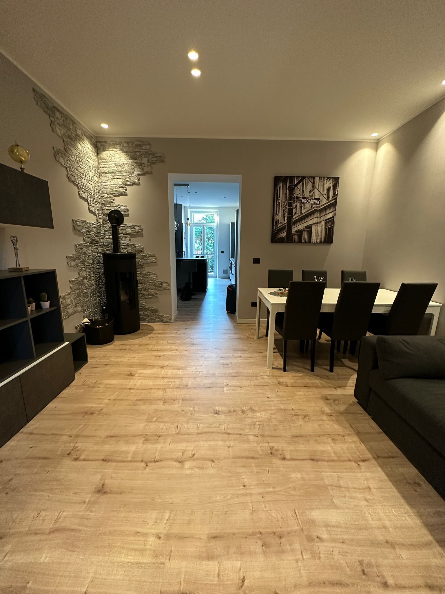 Un soggiorno con pavimento in legno, tavolo e sedie