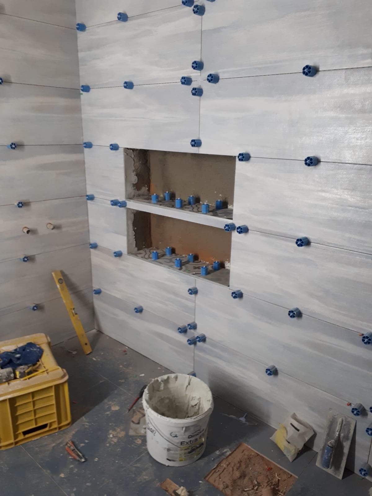 Un secchio di cemento è appoggiato sul pavimento di un bagno in costruzione.