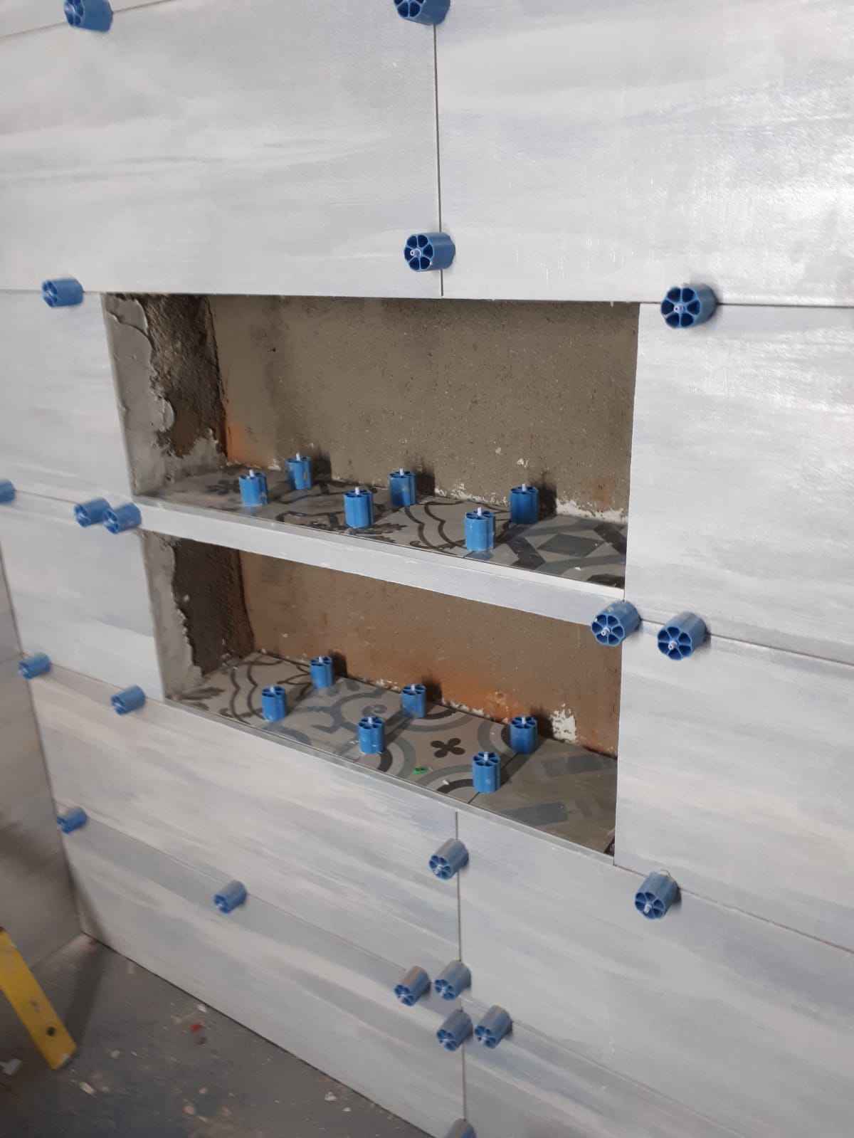 Un muro con piastrelle bianche e distanziatori blu.