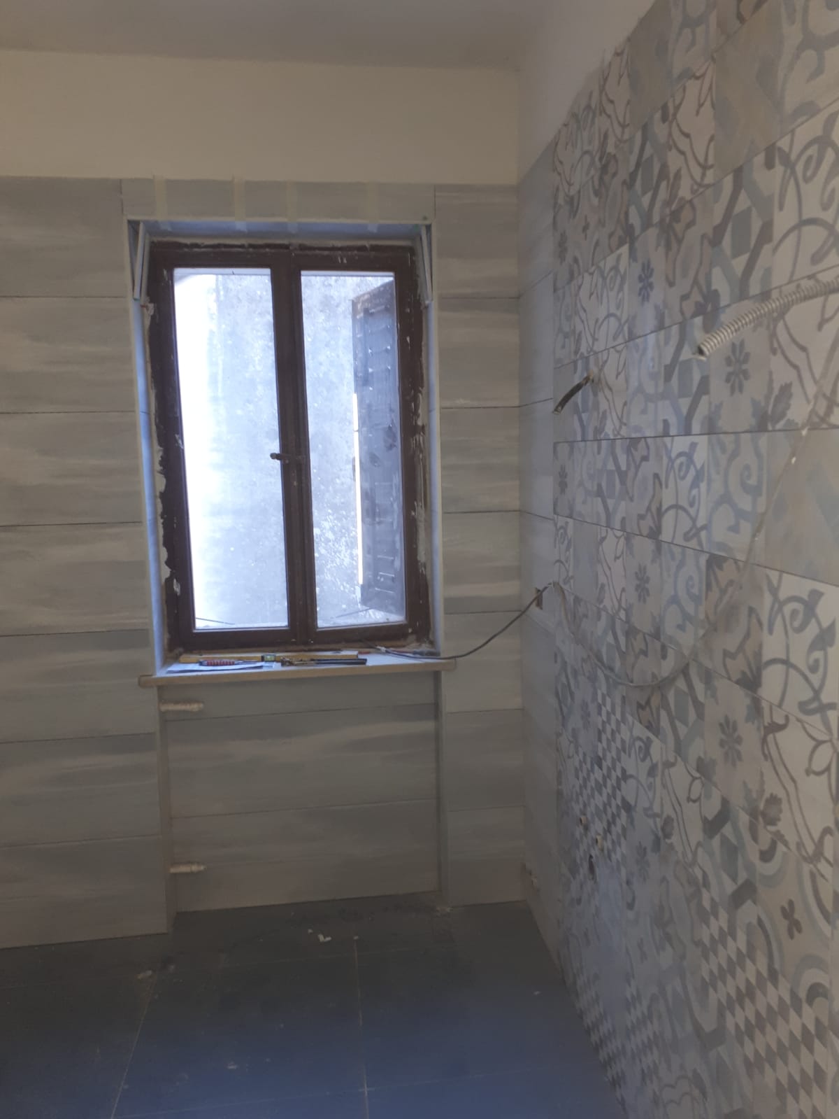 Una stanza con una finestra e pareti piastrellate.