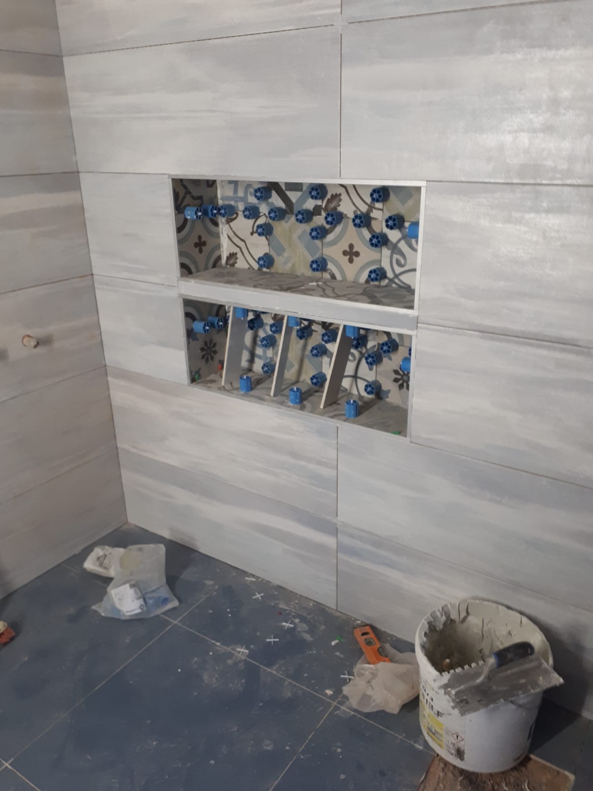 Un bagno in costruzione con piastrelle e un secchio di cemento.