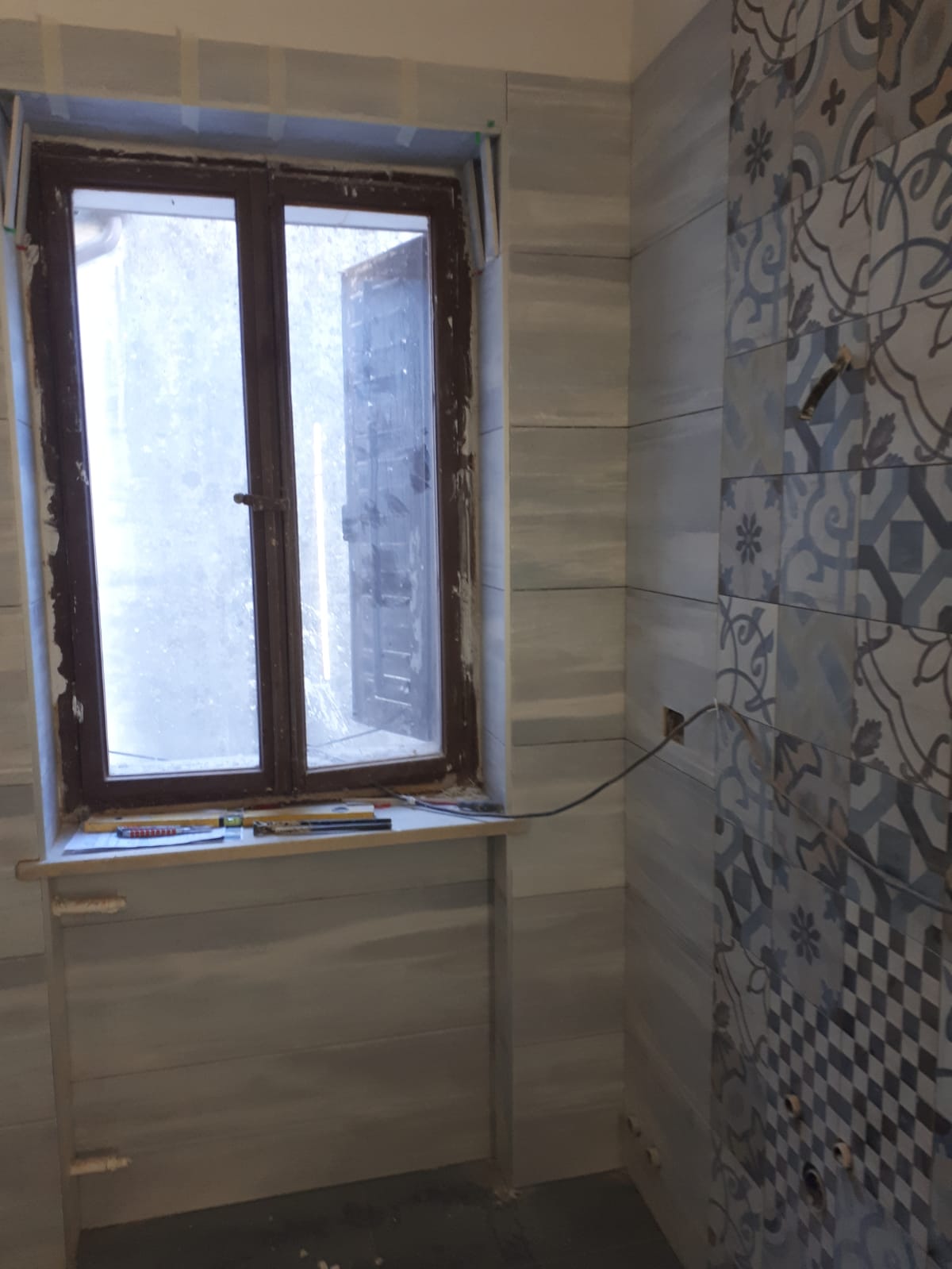 Un bagno con finestra e piastrelle sul muro.