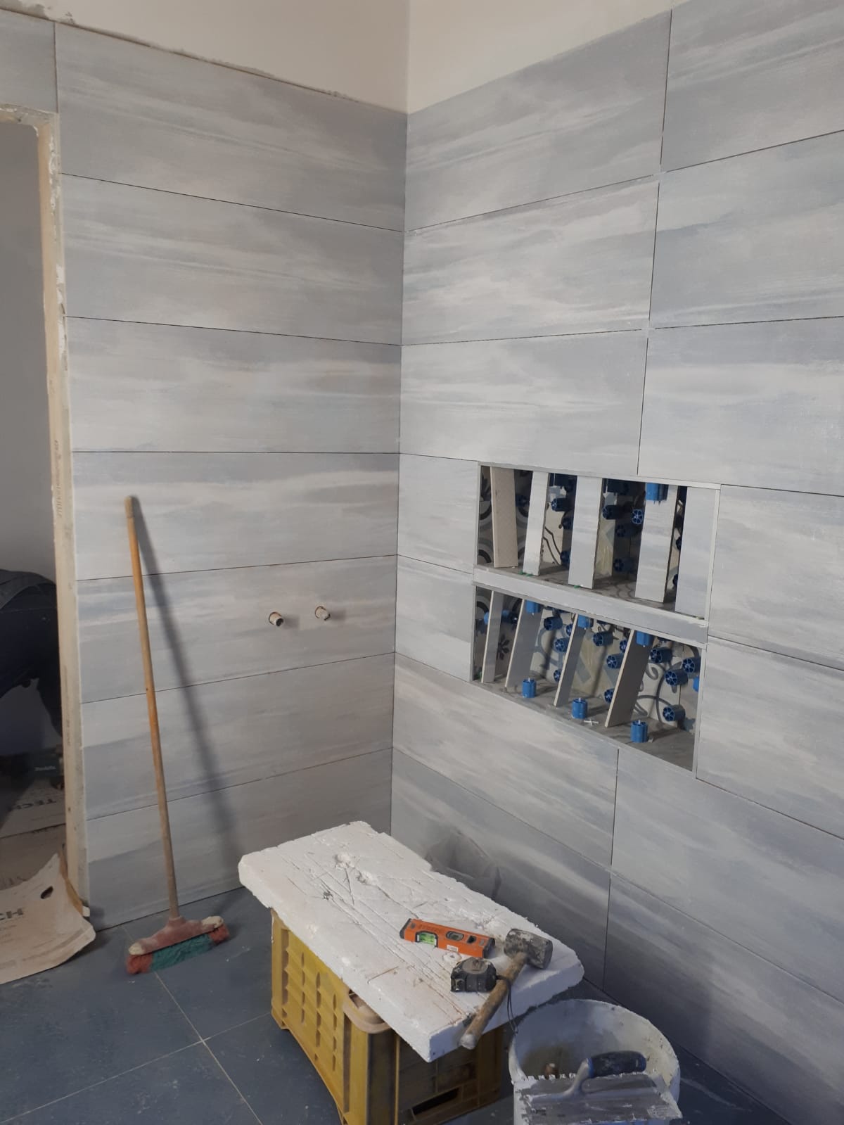 Un bagno in costruzione con una panca e una scopa.