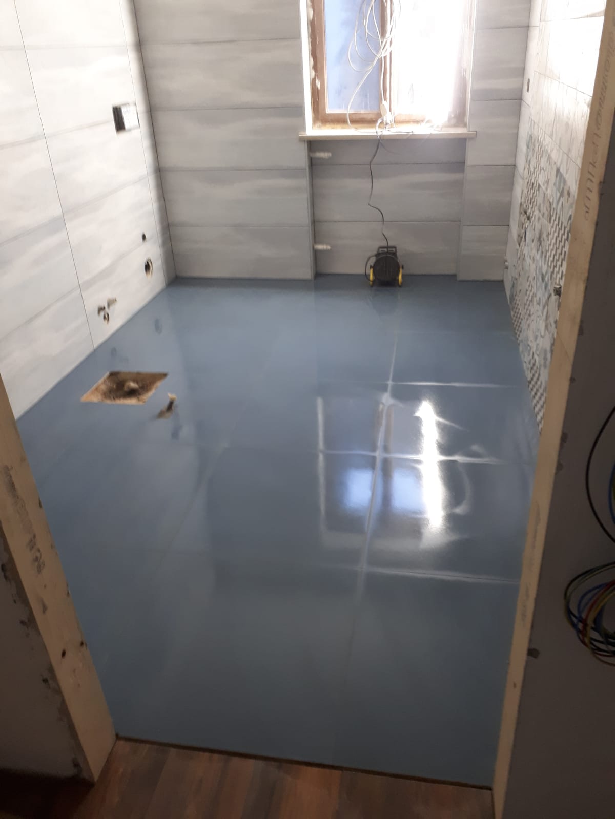 Un bagno con il pavimento blu e una finestra.