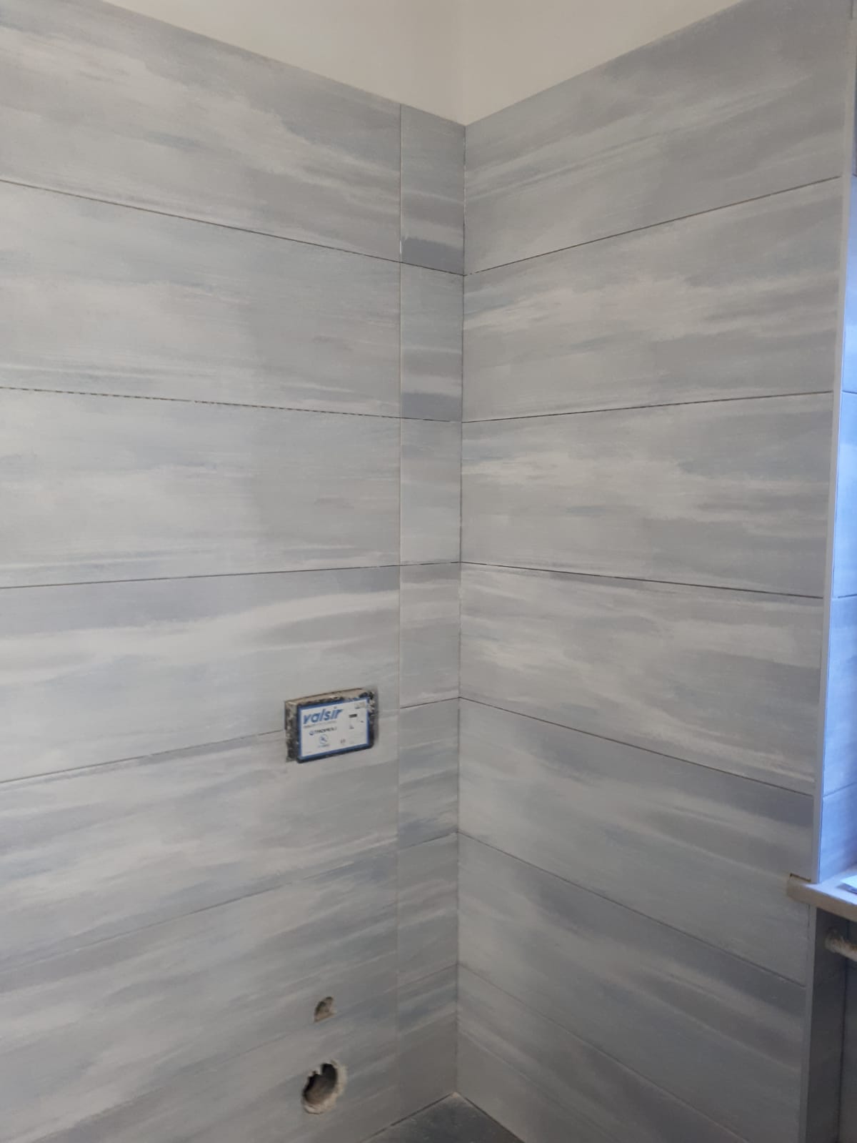 Un bagno con piastrelle grigie alle pareti e un water.