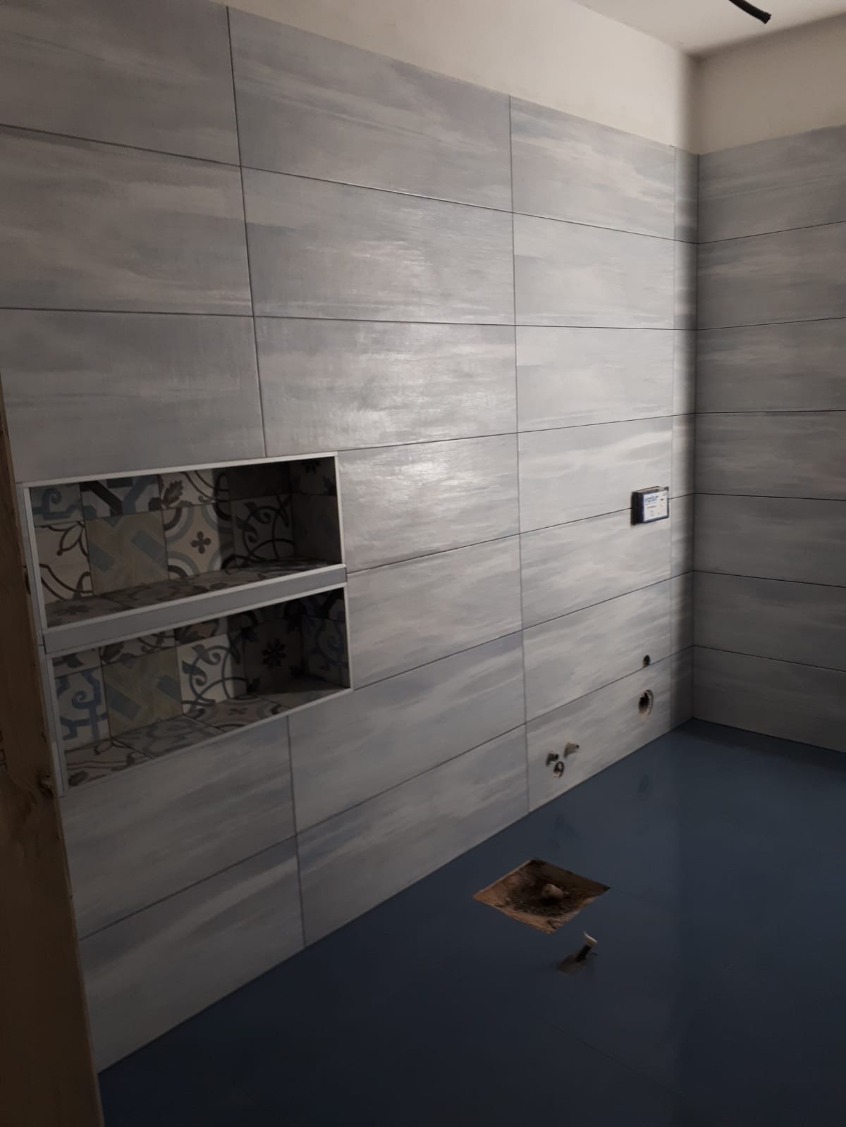 Un bagno con piastrelle grigie alle pareti e pavimento blu.