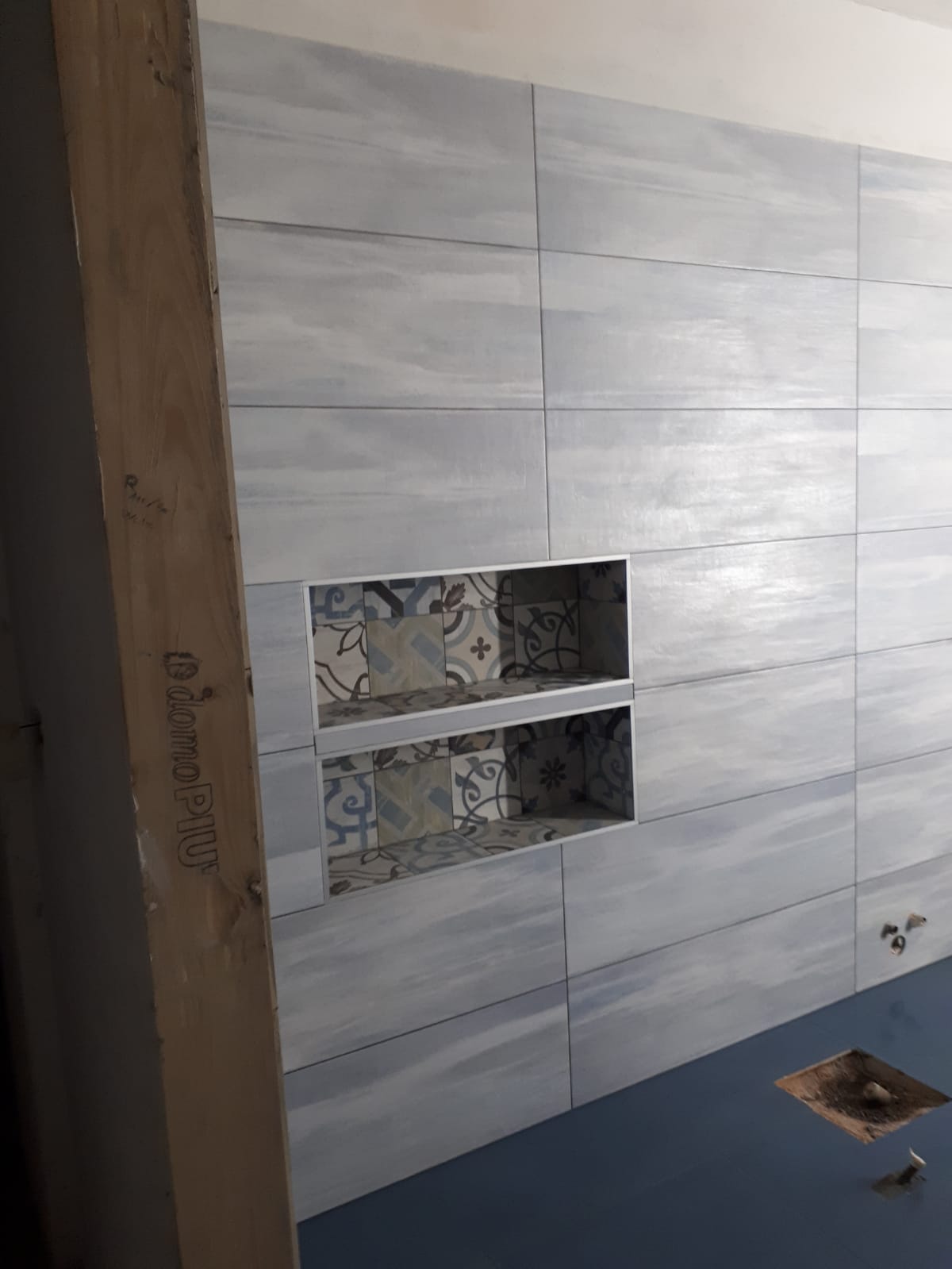 Una parete del bagno con piastrelle e due nicchie.