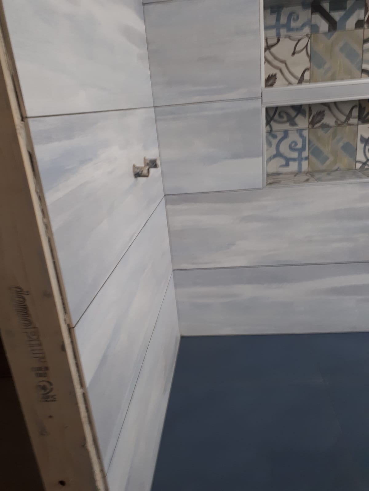 Un bagno con piastrelle bianche e pavimento blu.