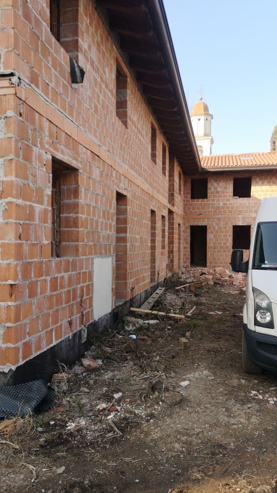 Un furgone bianco è parcheggiato davanti a un edificio in mattoni in costruzione.