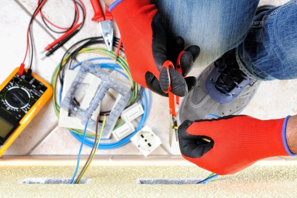 Una persona che indossa guanti rossi sta lavorando sui cavi elettrici.