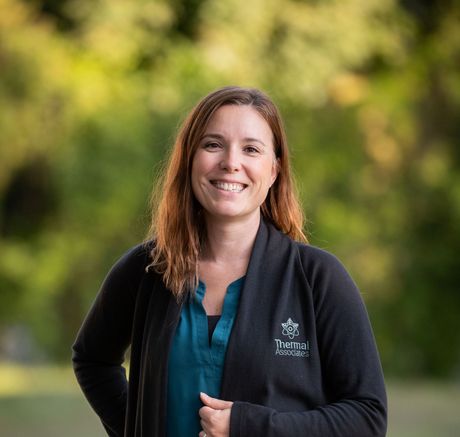 andrea devitt - a woman wearing a black cardigan and a blue shirt is smiling for the camera.