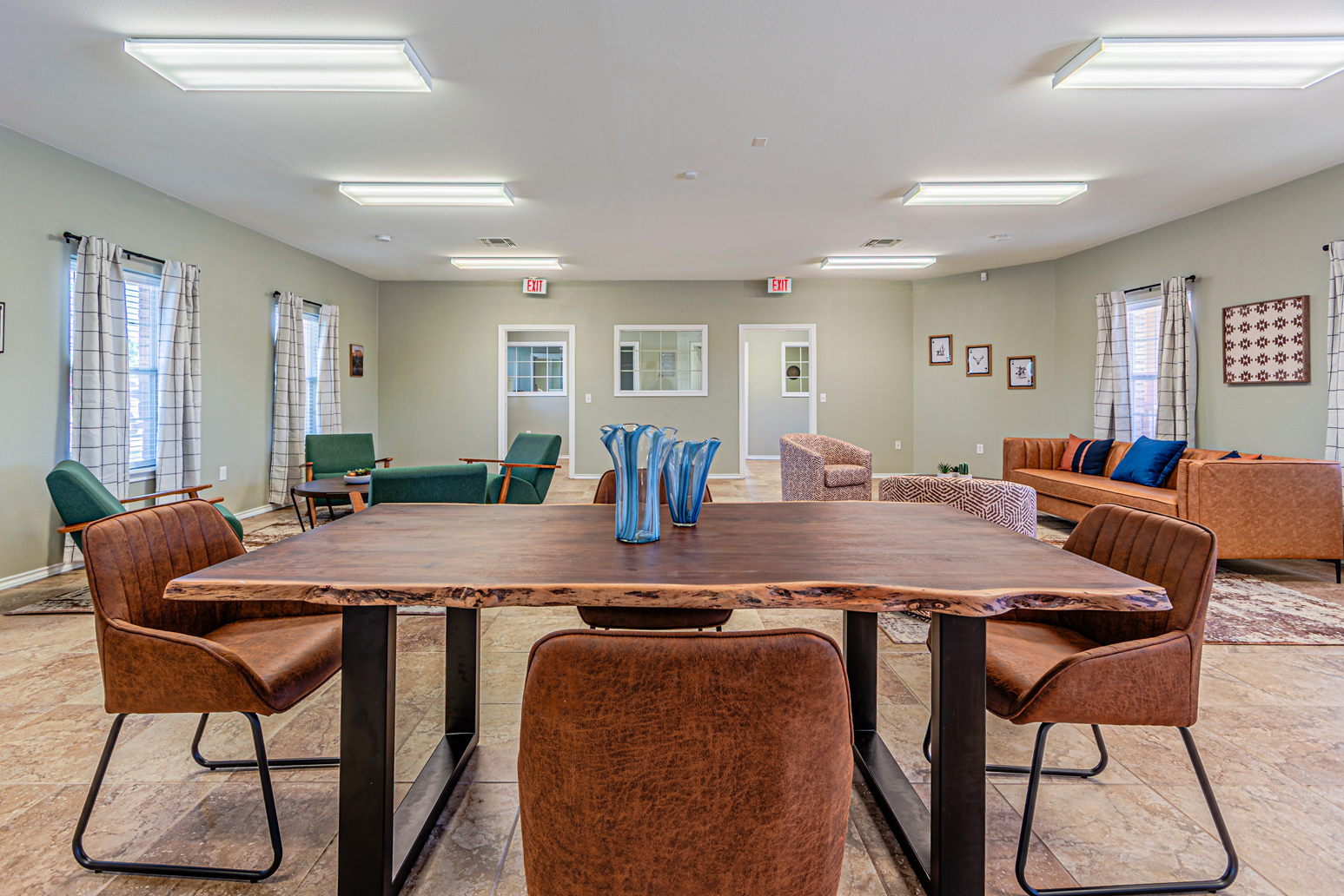 Large meeting room with a round table, brown chairs, and blue table covers under fluorescent lights