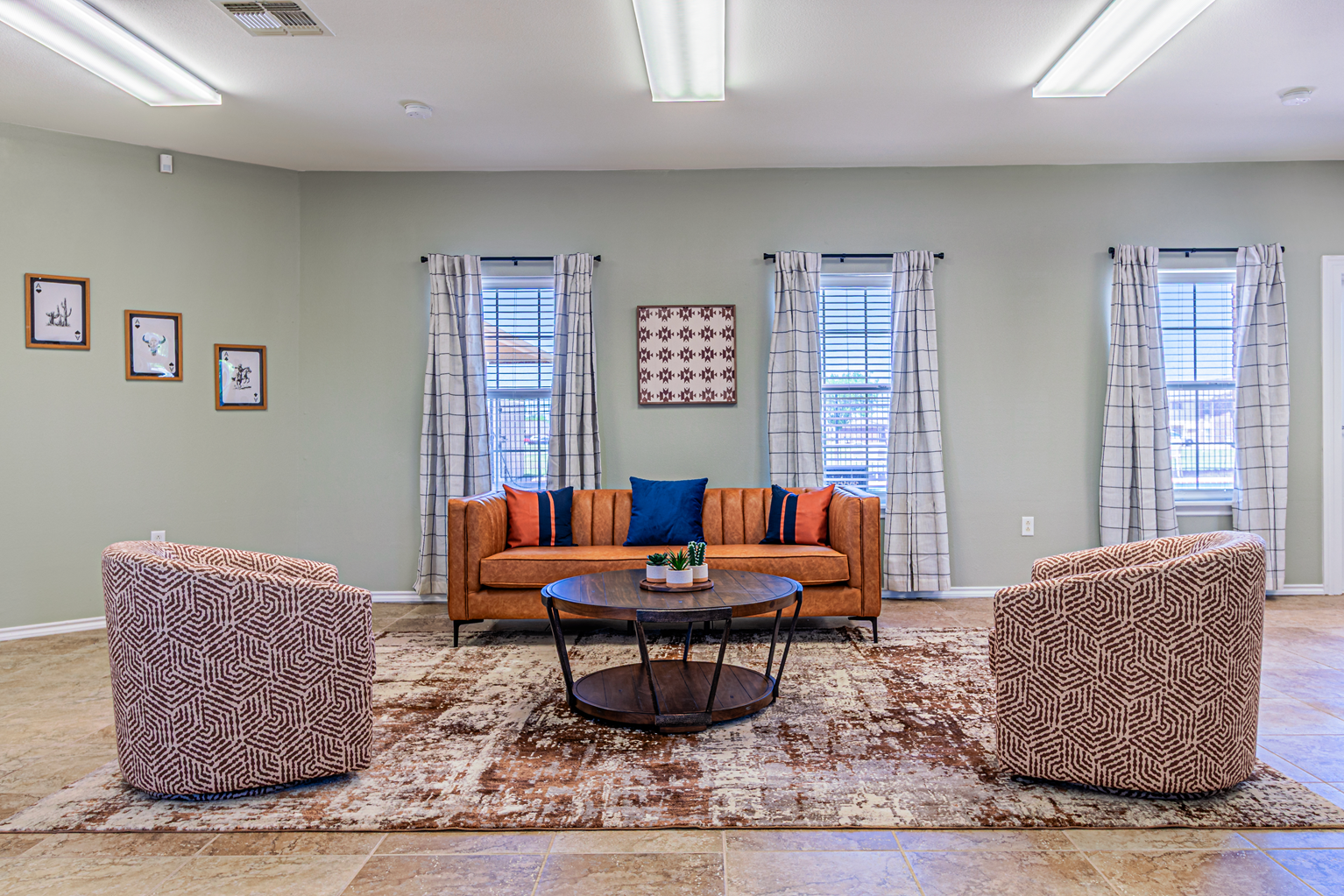 Living room with orange sofa, two patterned chairs, and a round coffee table on a rug.