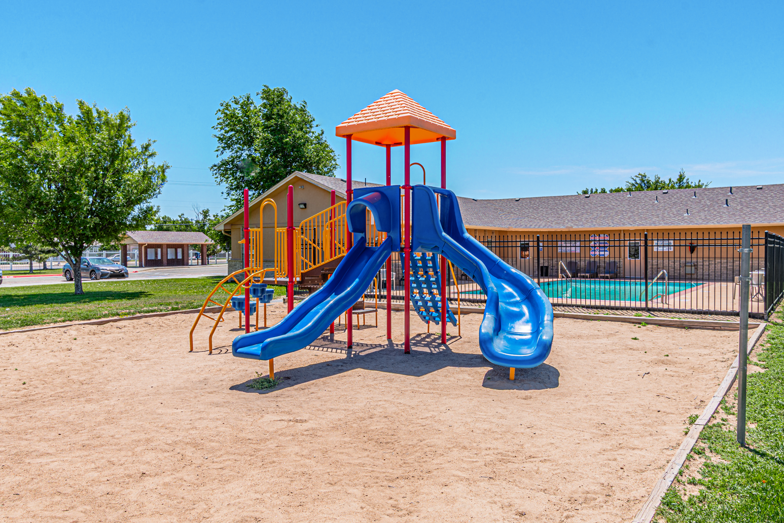 Apartment building with brick exterior and green lawn on a sunny street corner