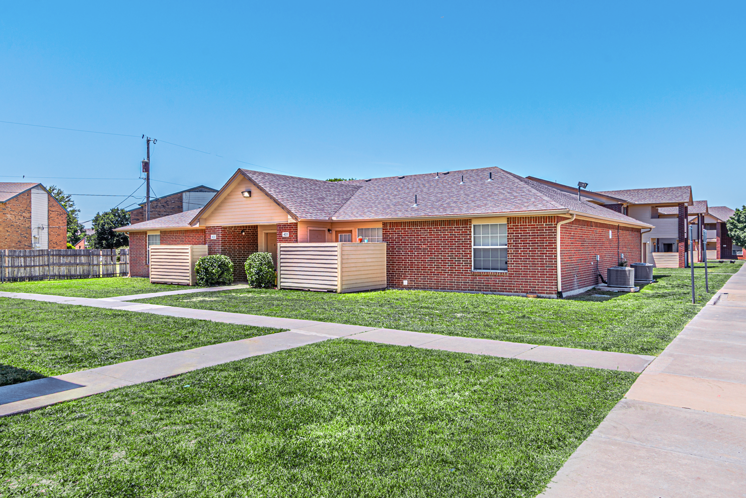 Single-story brick house with a small lawn and sidewalk on a sunny day