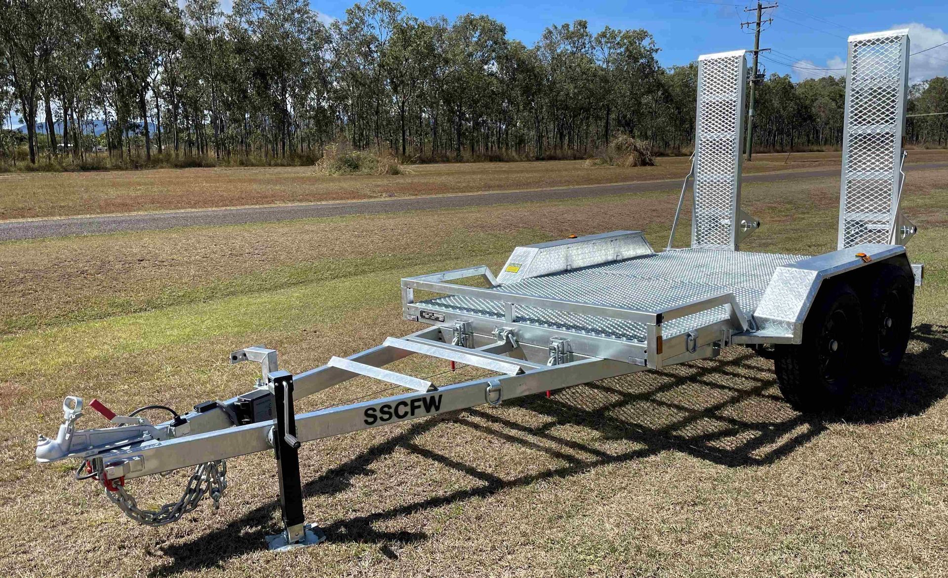 A trailer with a ramp attached to it is parked in a field.