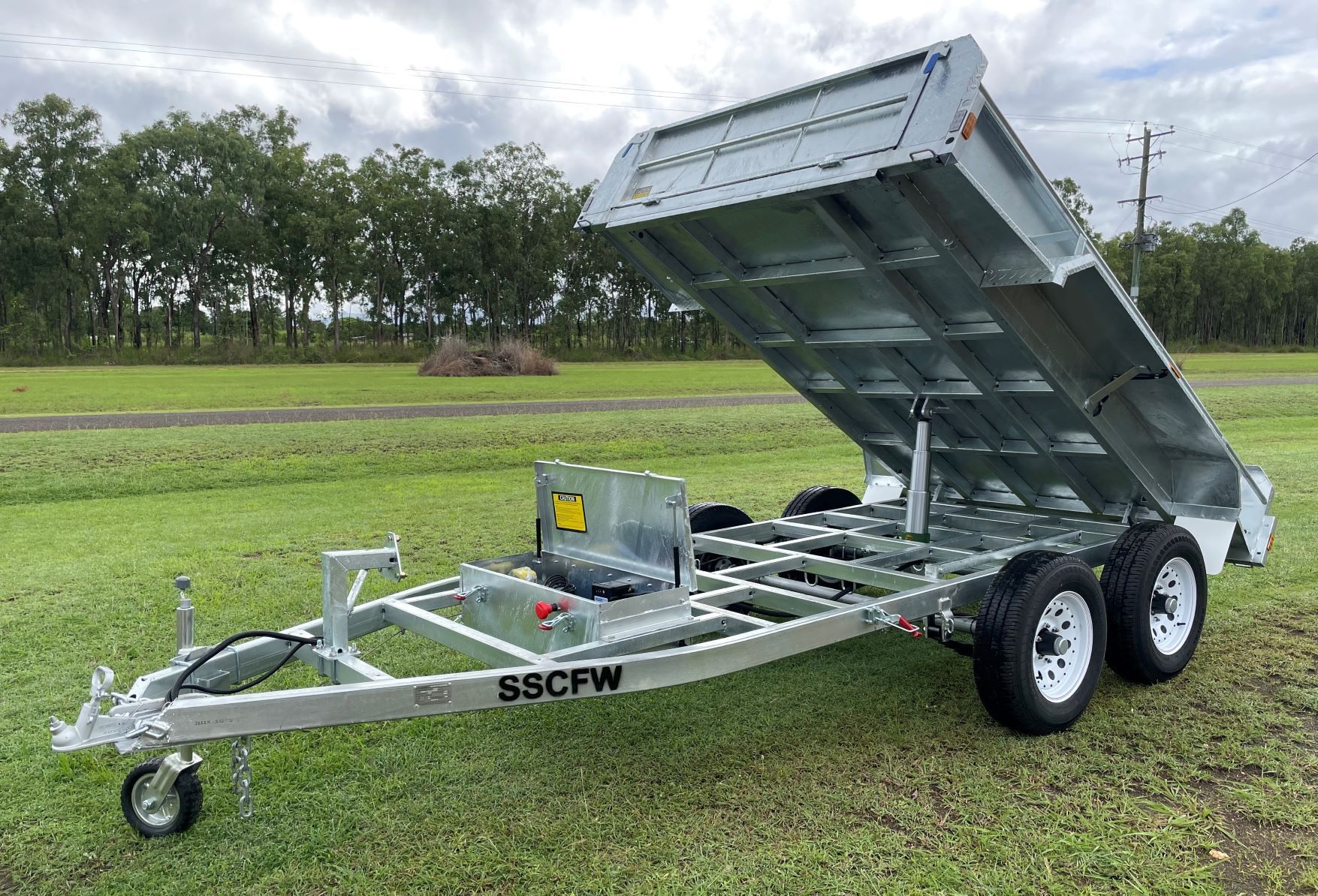 A dump trailer is sitting on top of a lush green field.