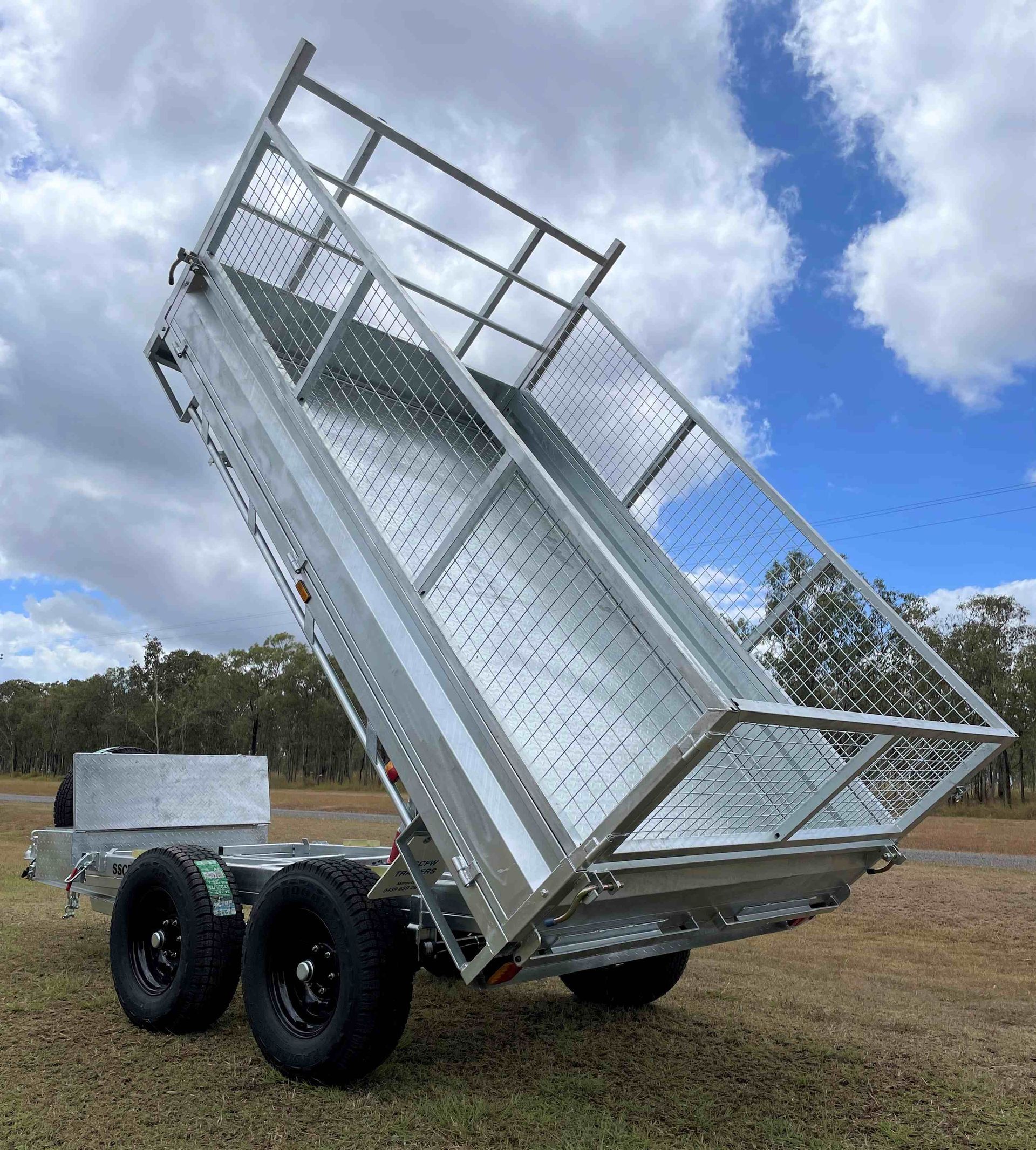 A dump trailer is parked in a field with a blue sky in the background.