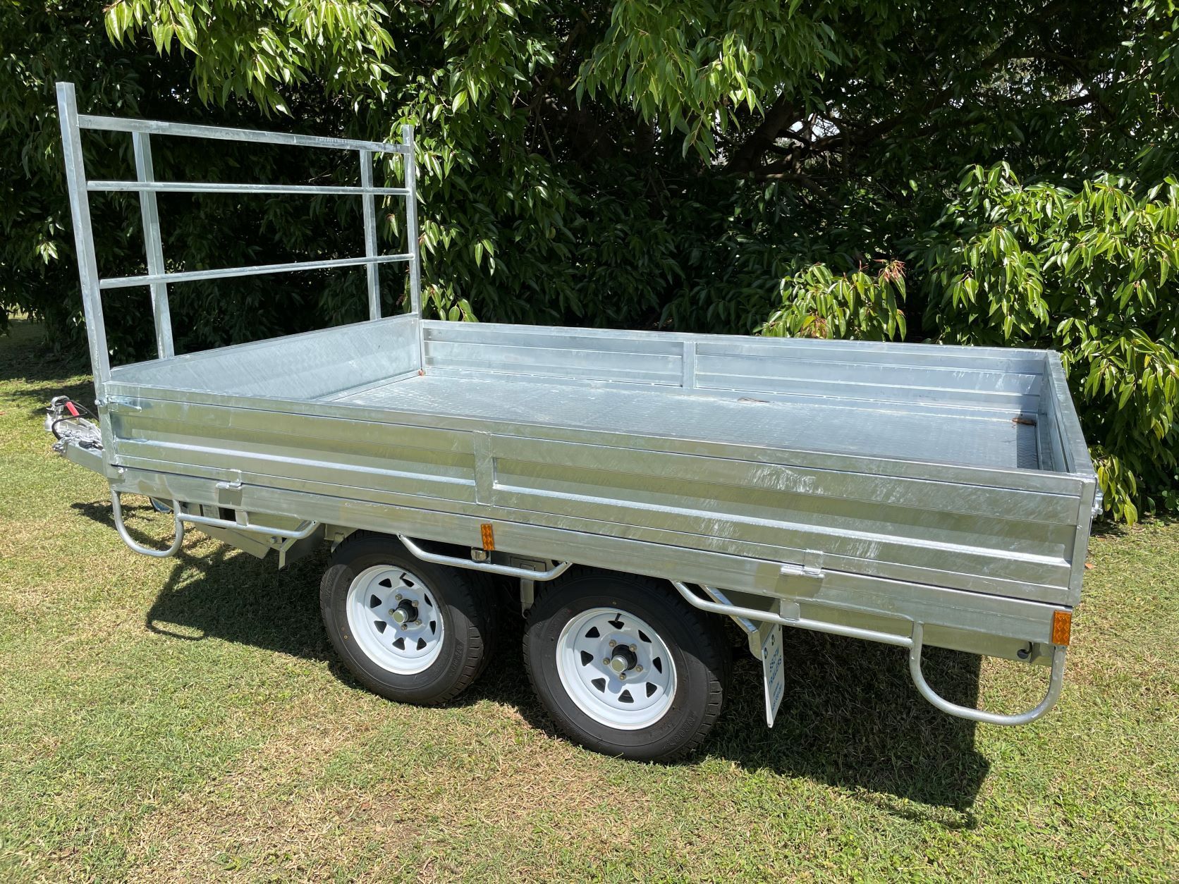 A trailer is sitting on top of a lush green field.