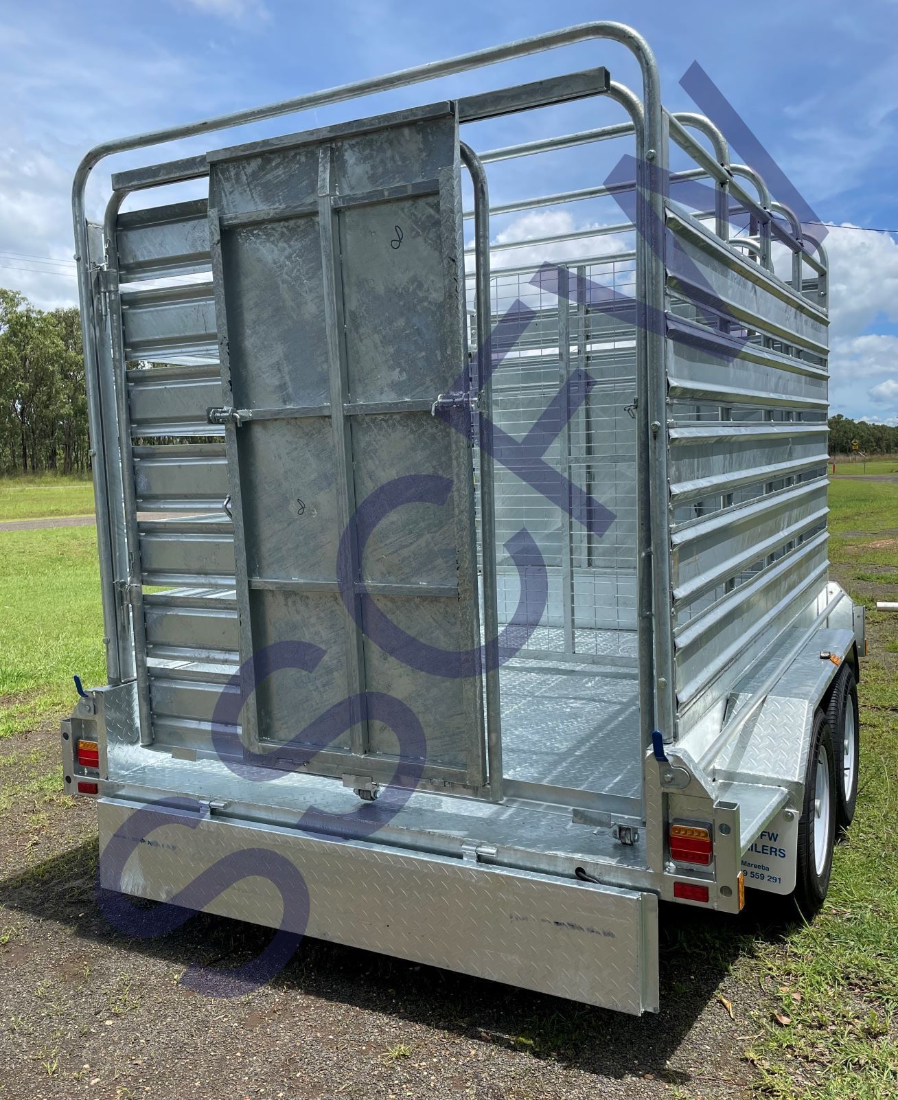 A metal trailer is parked in a grassy field.