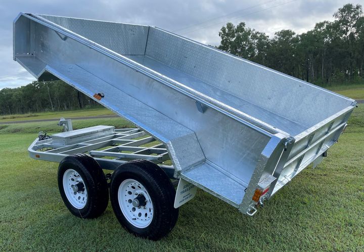 A dump trailer is sitting on top of a lush green field.