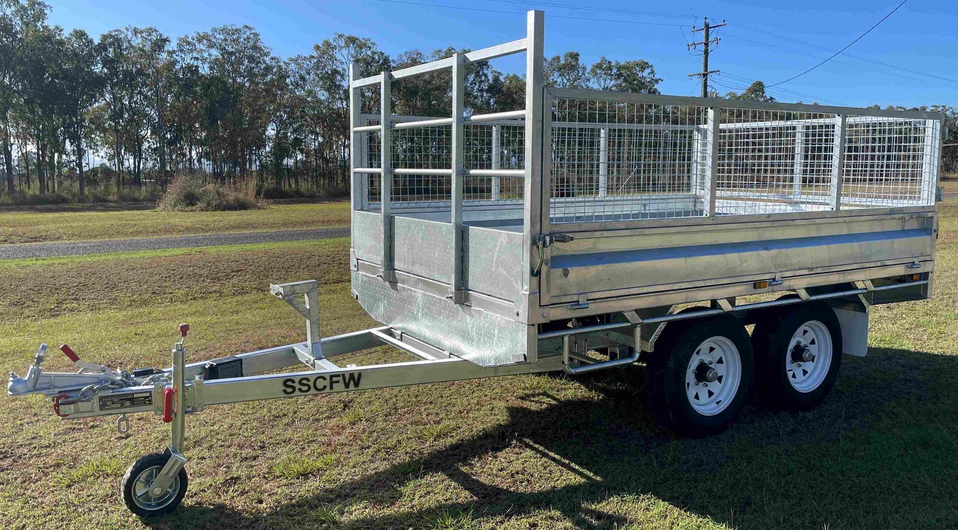 A trailer is parked in a grassy field with trees in the background.