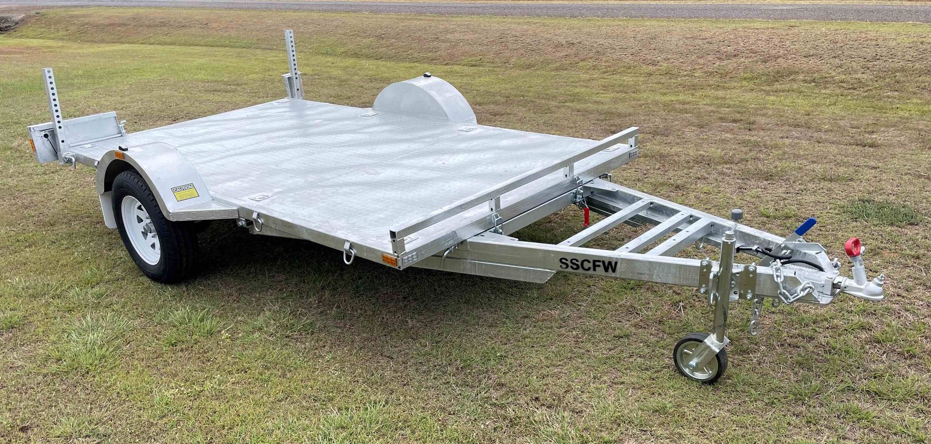 A motorcycle trailer is parked in a grassy field.