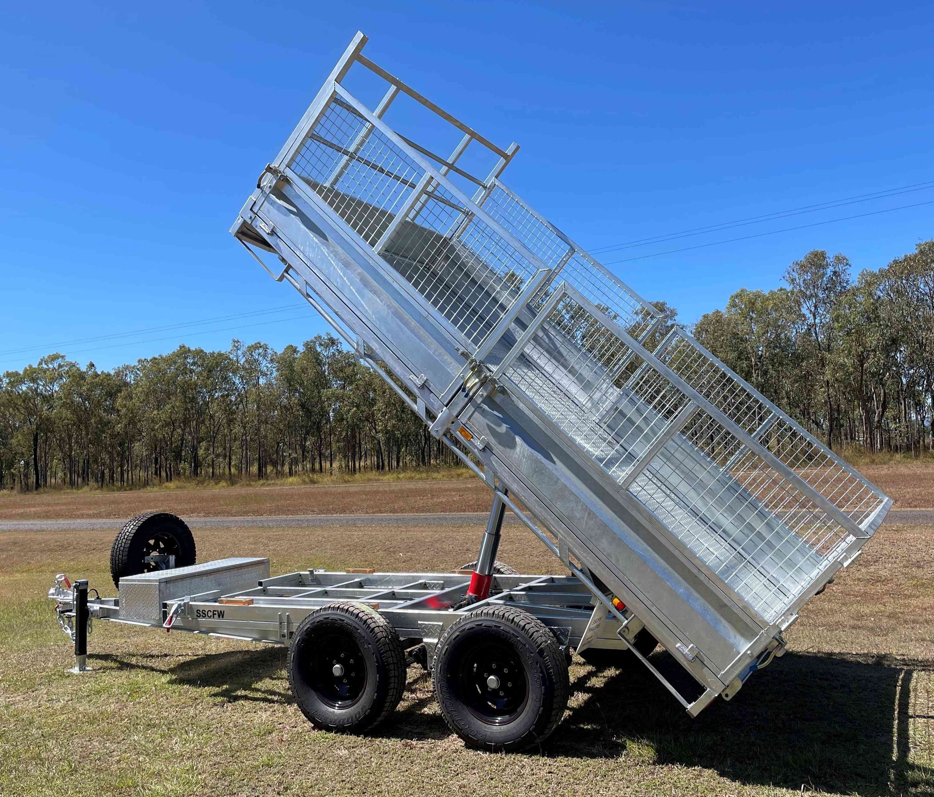 A dump trailer is parked in a grassy field.