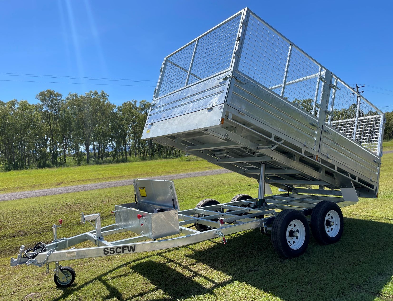 A trailer is sitting on top of a lush green field.