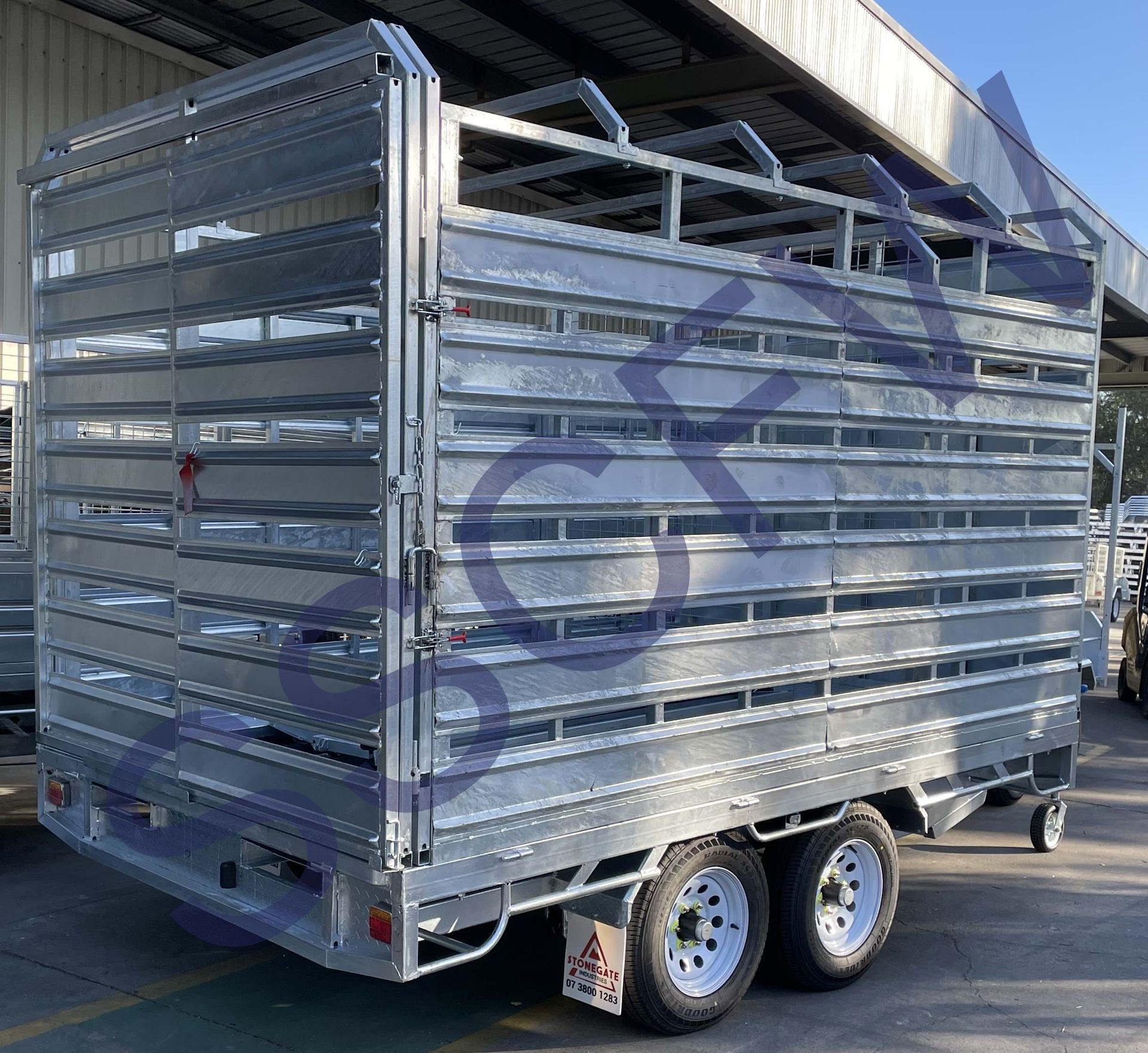 A trailer with a fence on the back is parked in front of a building.